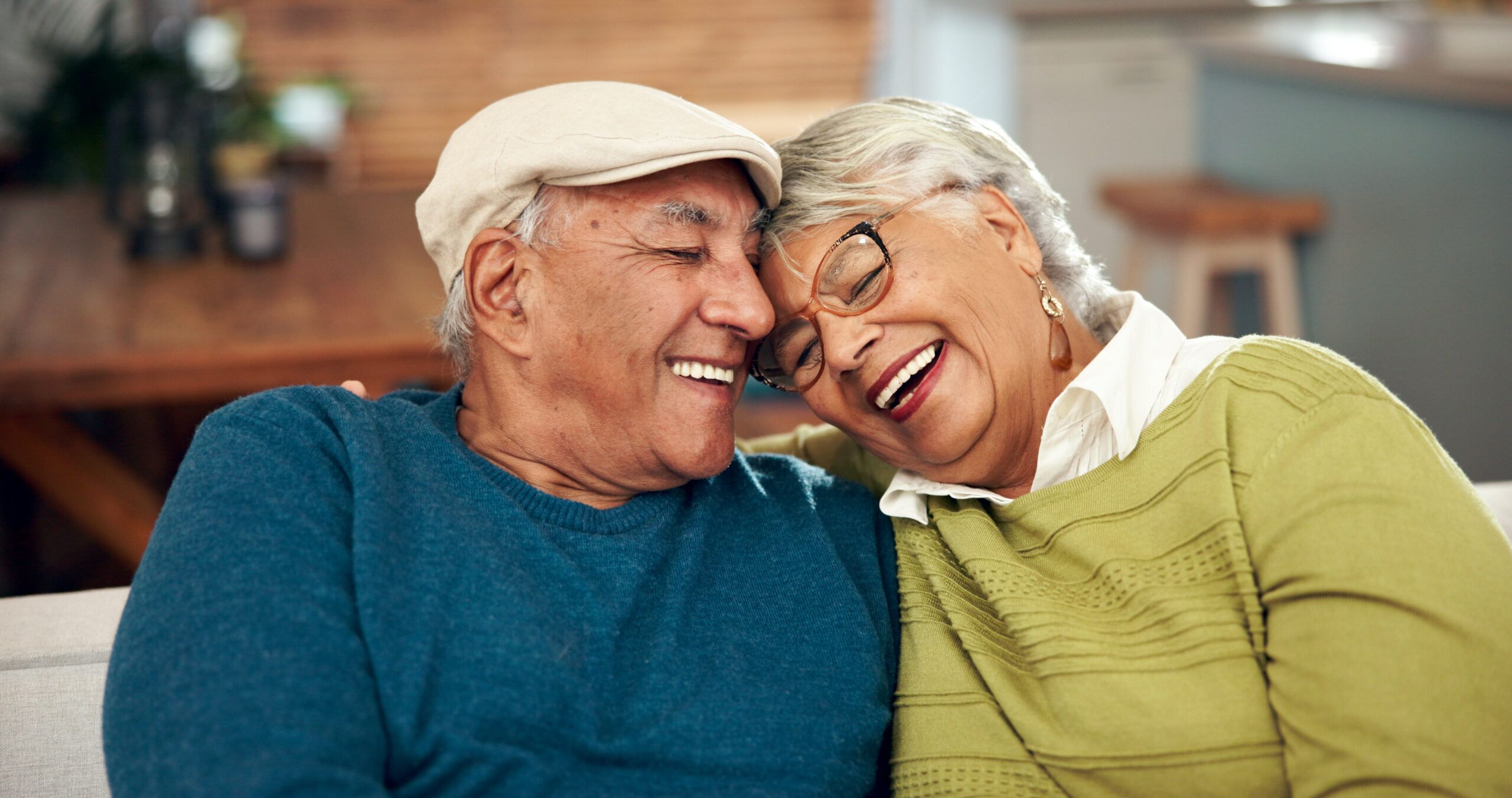 happy-mature-couple-and-hug-with-love-on-sofa-for-2024-07-11-23-01-48-utc Senior couple embracing on couch in their apartment receiving Alzheimers care in Fresno CA