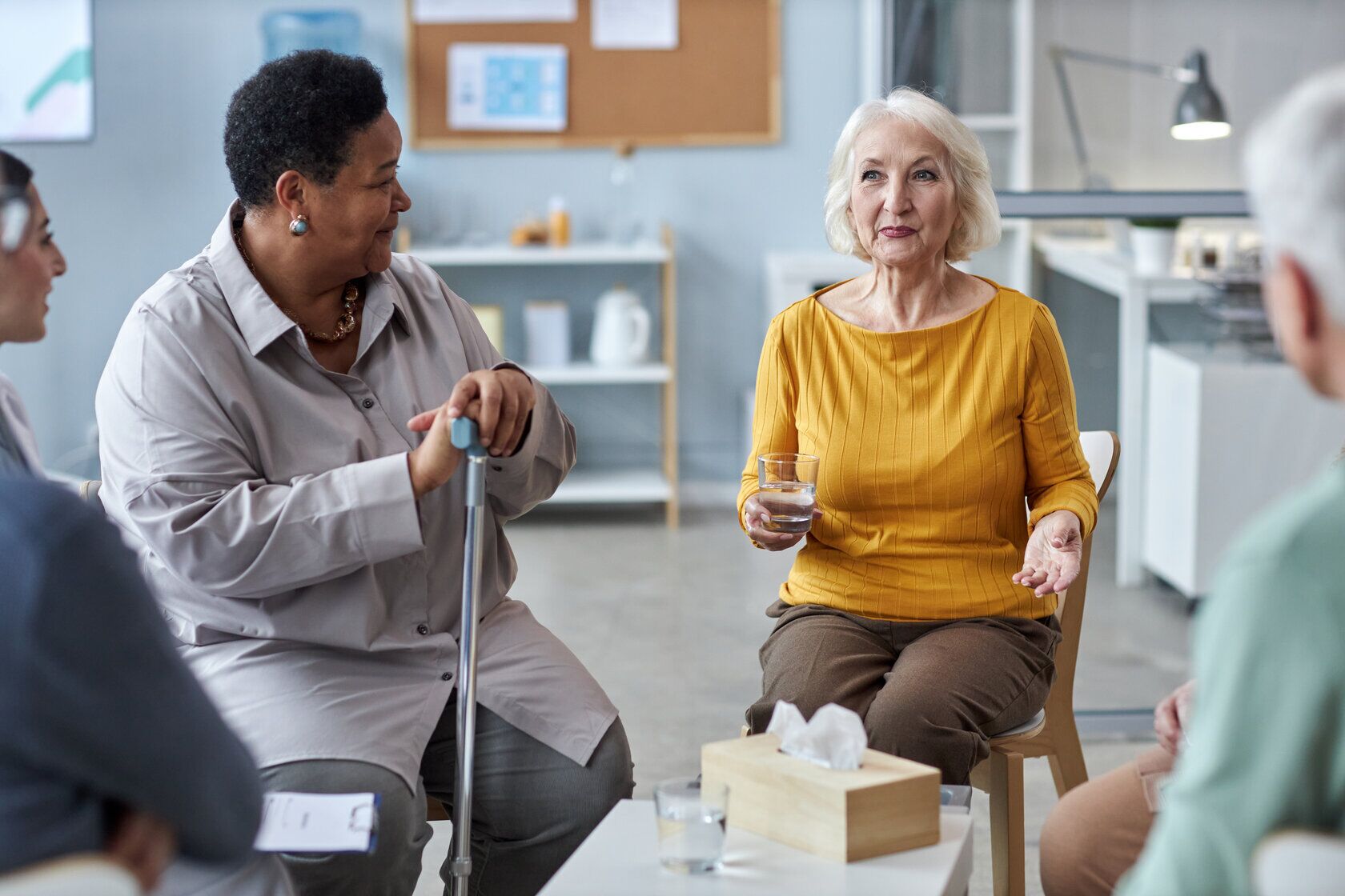 Two senior women sharing stories at mental health support group Group of seniors in dementia care in Fresno, CA