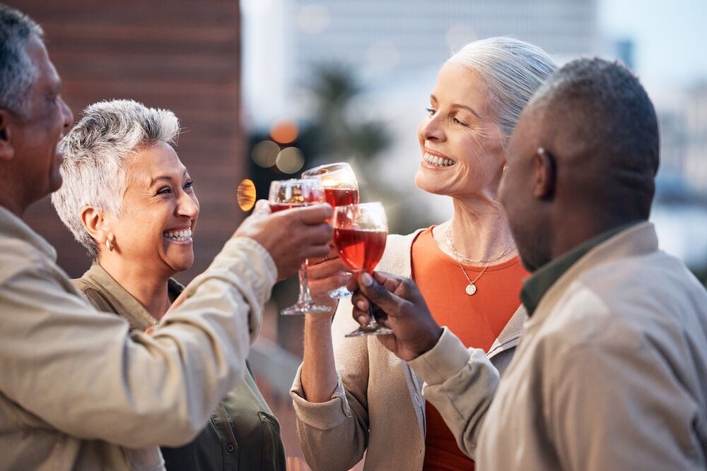 Friends, senior people with wine and retirement party, cheers and glasses with happiness, celebrati Friends sharing wine and enjoying Assisted Living Fresno ca