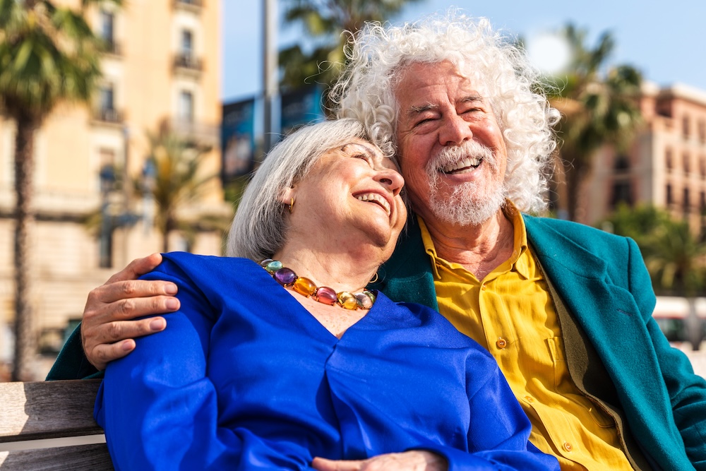 Senior couple of old people dating outdoors Senior couple outside on bench enjoying Assisted Living in Fresno, CA