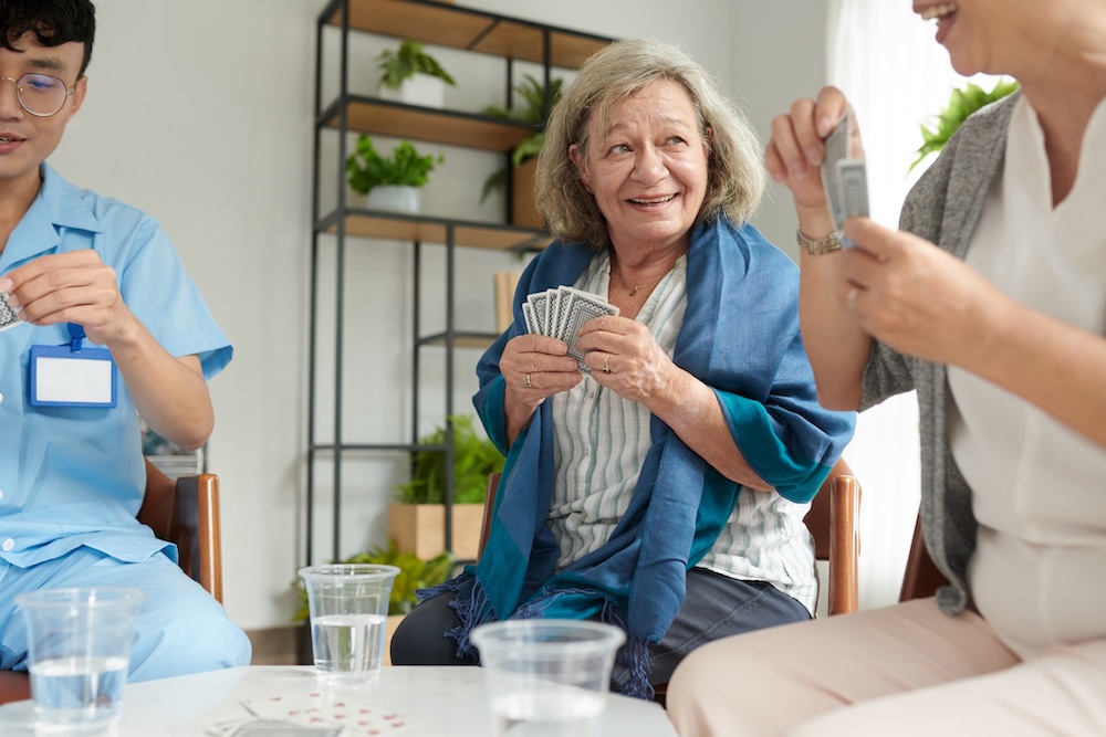 Senior woman playing a card game with other residents at a Senior Assisted Living Fresno